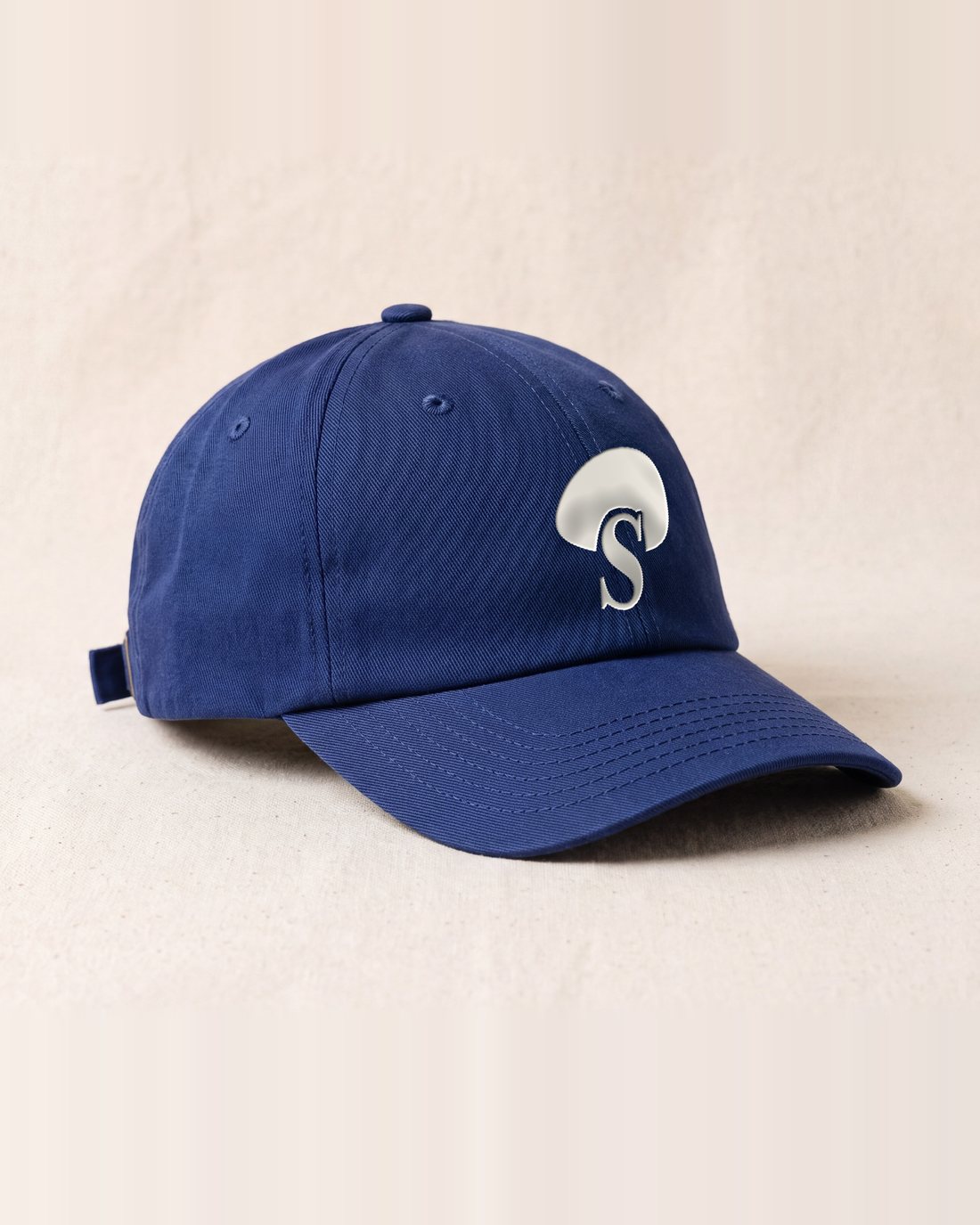 The indigo cap with the Cap of Gills embroidered in raw cotton on the front.